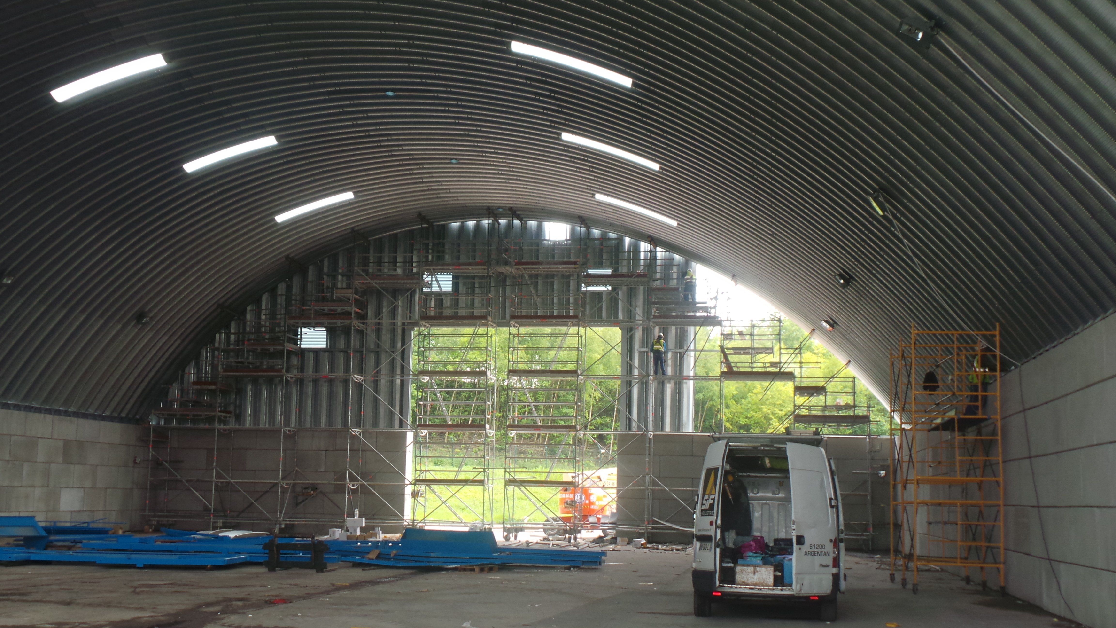 Intérieur d’un dôme acier BROOF T3 autoportant avec stockage vrac et circulation d’engins, structure sans poteaux idéale pour logistique industrielle