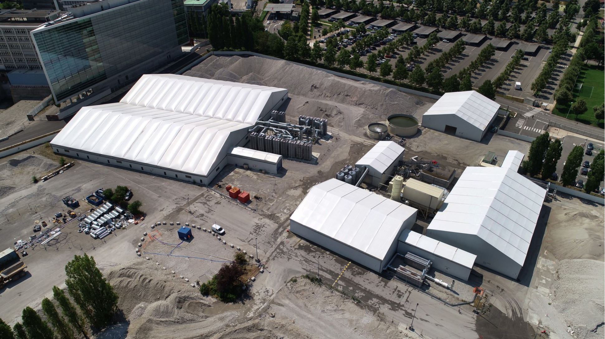 Plateforme industrielle de traitement des sols pollués avec bâtiments modulaires métallo-textiles et zones de dépollution vues par drone