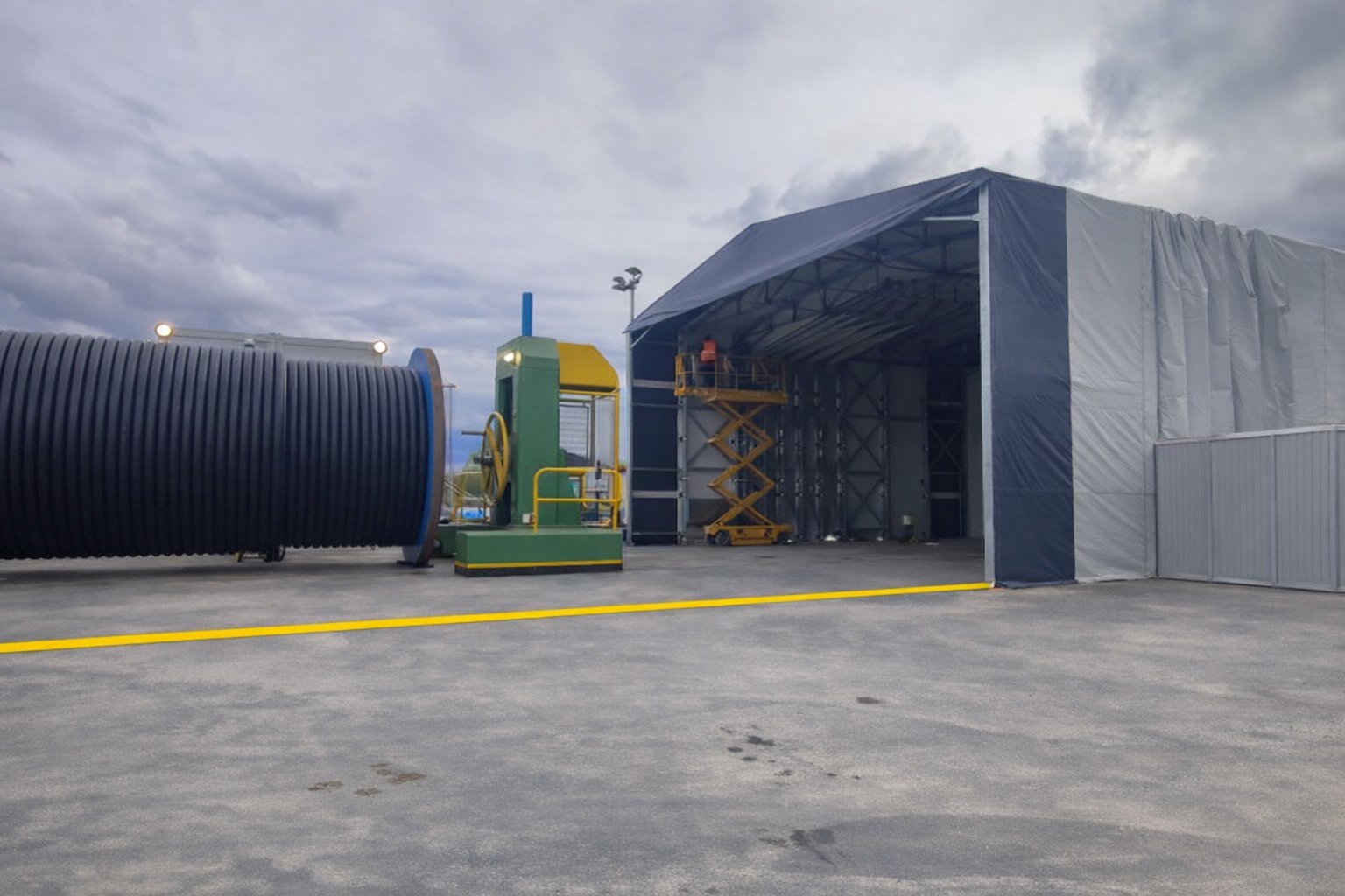 Bâtiment rétractable industriel à moitié  replié pour stockage vrac avec accès latéral et structure mobile sur rails