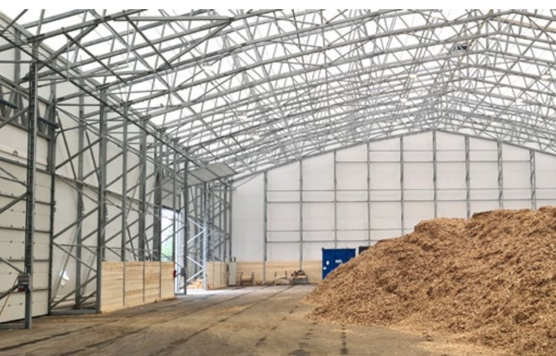 Hangar de stockage vrac industriel ouvert avec accumulation de bois ou déchets en vrac sous structure métallotextile