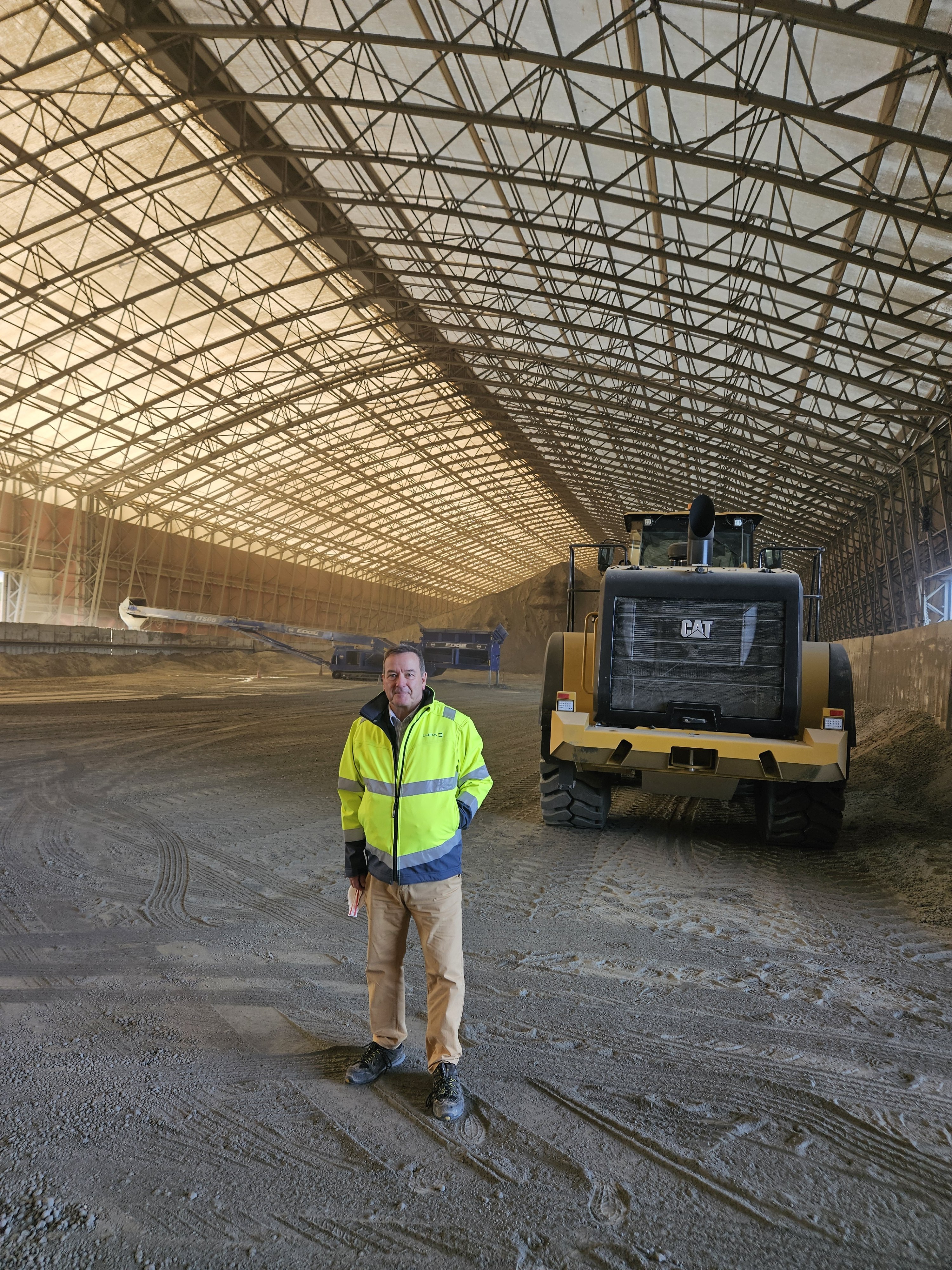 Hangar de stockage vrac industriel ouvert avec accumulation de bois ou déchets en vrac sous structure métallotextile