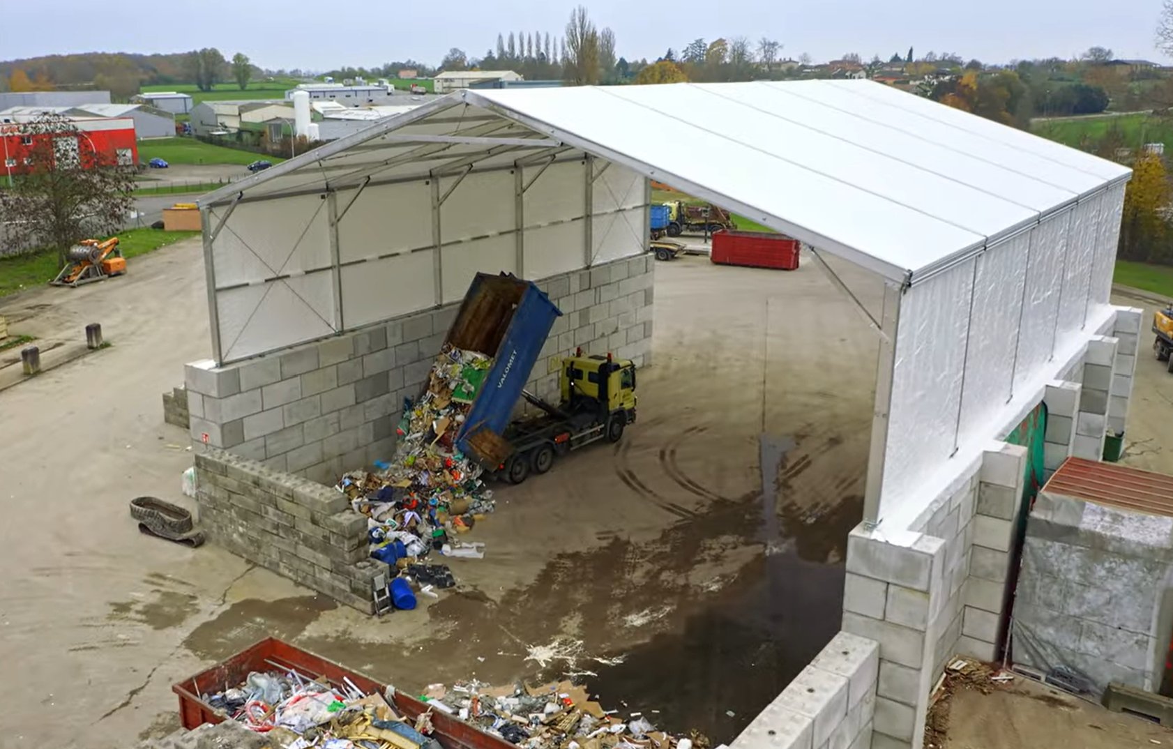 Bâtiment industriel deux pans sur blocs béton LEGO pour stockage vrac déchets avec structure métallo textile avec  fondation légères